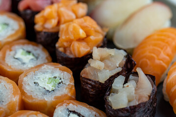 Sushi rolls prepared by professional asian chef with traditional Japanese ingredients. Salmon fish, rice, vegetables, sesame seeds.  Sushi cooking and seafood making concept