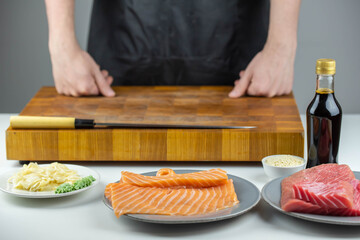 Close up of sushi chef hands preparing japanese food. Man cooking sushi at restaurant. Traditional asian seafood rolls on cutting board.