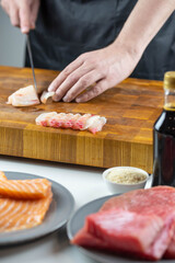 Close up of Chef cook hands chopping salmon fish for traditional Asian cuisine with Japanese knife. Professional Sushi chef cutting seafood for rolls.