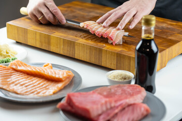 Close up of Chef cook hands chopping salmon fish for traditional Asian cuisine with Japanese knife. Professional Sushi chef cutting seafood for rolls.