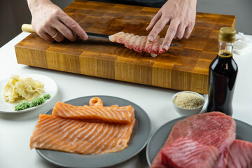 Close up of Chef cook hands chopping salmon fish for traditional Asian cuisine with Japanese knife. Professional Sushi chef cutting seafood for rolls.