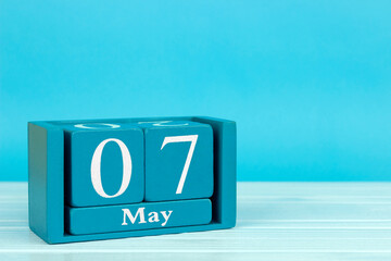wooden calendar with date May 7 on blue wooden background, World AIDS Orphans Day