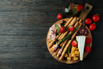 Board with grissini and snacks on wooden background
