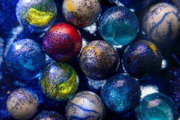 Fototapeta na wymiar Macro photography of a bunch of marbles with glitters. The marbles have different colors and sizes, creating a colorful and shiny display 