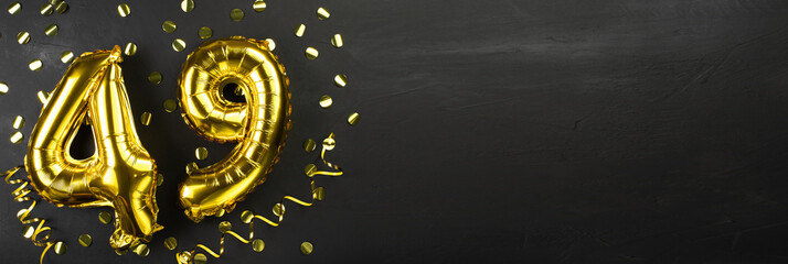 golden foil balloon number forty nine. Birthday or anniversary card with the inscription 49. Black concrete background. Anniversary celebration. Banner.