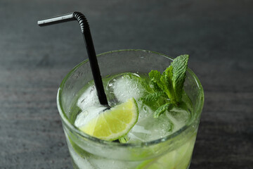 Glass of mojito cocktail on dark wooden background