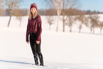 Hübsches junges Teenager Mädchen posiert im hellen, weißen Schnee vor blauem Himmel