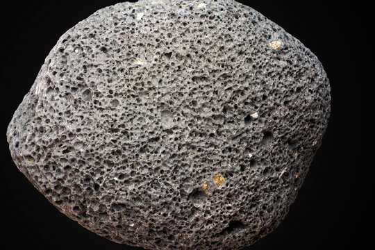Porous volcanic rock isolated on black background, gray pumice stone texture for spa, exfoliation, skincare, and geological research, natural basalt mineral specimen