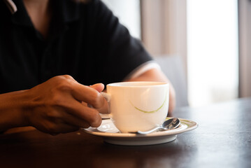 cropped shot of barista holding cup of aromatic coffee in hand