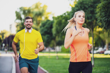 Young couple is jogging on running track in park.