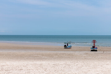 Two fishing boats moored on the shore in the blue sky.