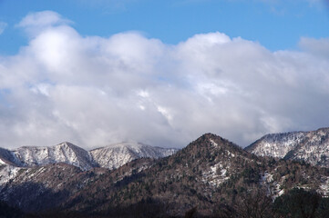 Fototapeta na wymiar 雲の浮かぶ青空と残雪の山脈。