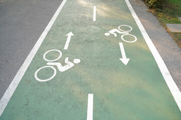 Fototapeta premium Bike lane signs painted onto a green bike lane. Bicycle lane in the park.