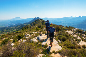 Fototapeta premium Hikers walking on mountains, in a sunny spring day. In La vall de laguar, Alicante (Spain)