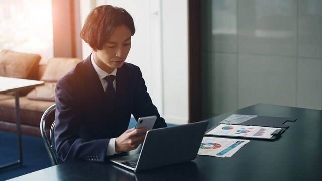 パソコンとスマホを見ながら深刻な表情のビジネスマン