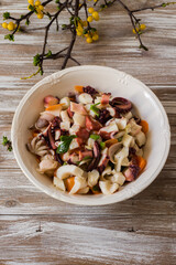 Seafood salad dressed and served in porcelain bowl on wooden background