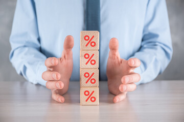 Businessman hand takes a wooden cube block depicting,shown the percentage symbol icon. Interest rate financial and mortgage rates concept.