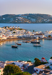 Fototapeta premium Beautiful sunset view of Mykonos, Cyclades, Greece, its port, windmills. Cruises, ship, whitewashed houses. Vacation, leisure, Mediterranean lifestyle