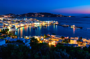 Beautiful night view of Mykonos, Greece, ships, port, whitewashed houses. Town lights up....
