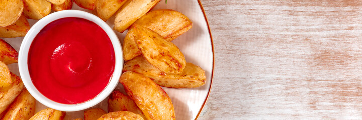 Baked potato wedges with ketchup panorama, overhead shot