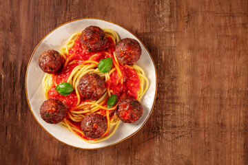 Meatballs with pasta and tomato sauce, shot from above on a dark rustic wooden background