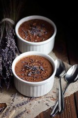 Chocolate vegan dessert - aquafaba mousse - egg free, non-dairy cocoa pudding or souffle decorated with lavender on dark moody background, closeup, vegan and vegetarian food concept