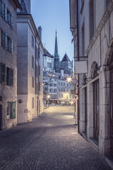 Fototapeta na wymiar Cityscape of the old town of Geneva at blue hour. View of Place du Bourg-de-Four and St. Pierre Cathedral from rue Etienne-Dumont at dawn.
