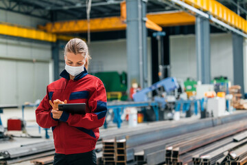 Woman working on digital tablet in factory hall, portrait.