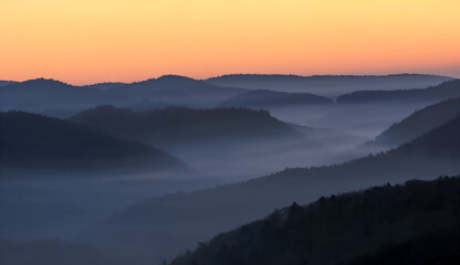 foggy, misty valley with orange sky before sunrise, beautiful orange yellow lighted sky