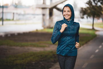 Beautiful adult woman is jogging outdoor on cloudy day in autumn.