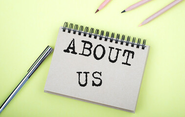 ABOUT US text on the notebook with pen on yellow background
