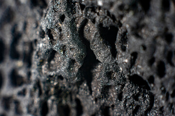 Close up of a black patterned volcanic rock. Background texture of a stone   