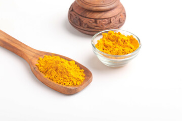 Turmeric powder in wooden spoon and glass bowl on white background.