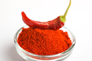 Dried red chilli and powder in glass bowl on white background.