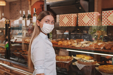 Woman looking to the camera, shopping at the bakery store, wearing medical face mask, copy space