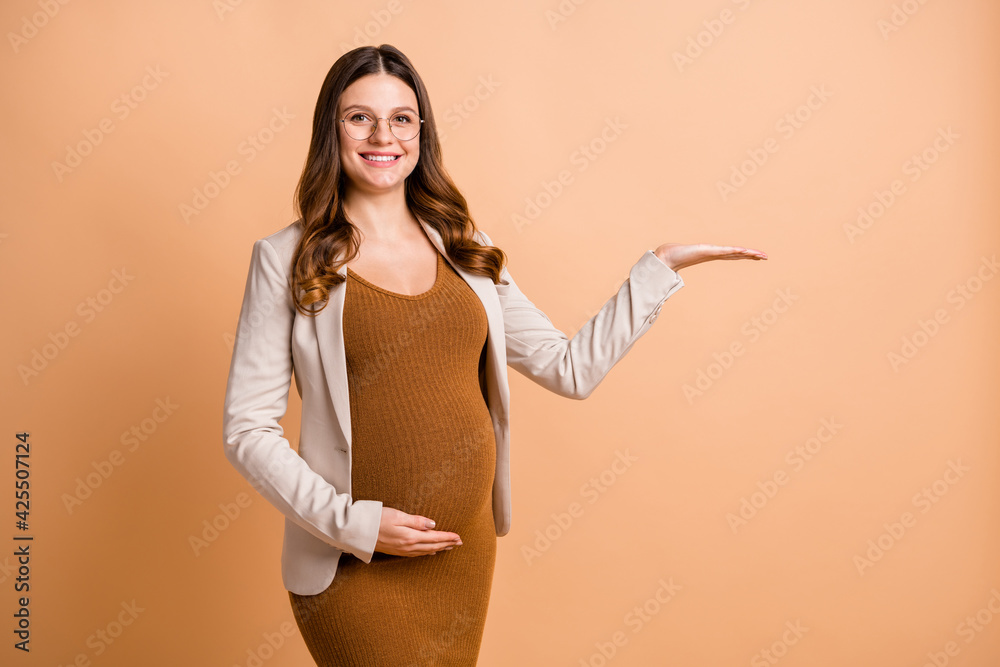 Sticker portrait of pretty cheery pregnant girl holding on palm copy empty place space ad isolated over beig