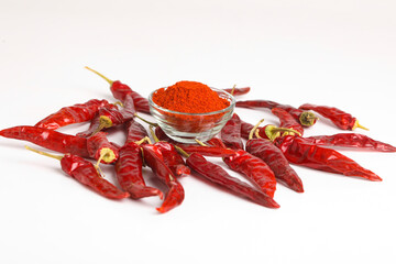 Dried red chilli and powder in glass bowl on white background.
