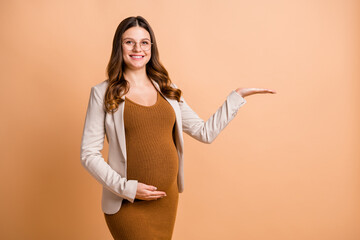 Portrait of pretty cheery pregnant girl holding on palm copy empty place space ad isolated over...