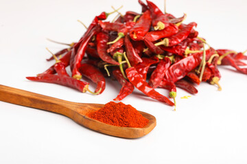 Dried red chilli and powder in wooden spoon on white background.