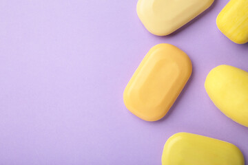 Different yellow soaps on purple . A lot of solid soap for hygiene and cleanliness.