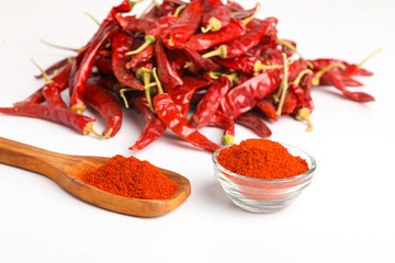 Dried red chilli and powder in wooden spoon on white background.
