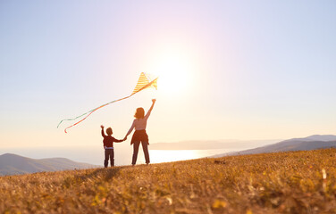 Happy family  mother and son  launch  kite on nature at sunset