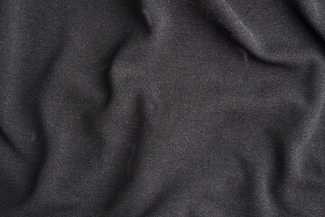 Background is made of black textile material, the texture of a piece of clothing.