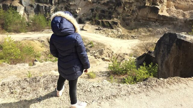 Young Caucasian Girl In Warm Jacket Standing on A Cliff in Sandstone Quarry Mine
