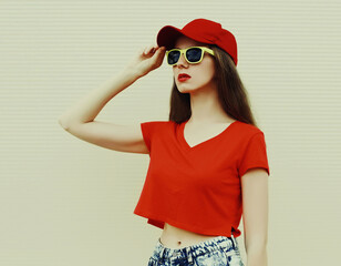 Portrait of young woman wearing a red baseball cap looking away in a city on a white background