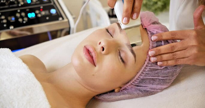 Beautician using electrical impulses for facial procedures. Beautiful woman receiving facial microcurrent treatment at spa salon.  Woman in spa salon. Woman in a spa salon on cosmetic procedures. 