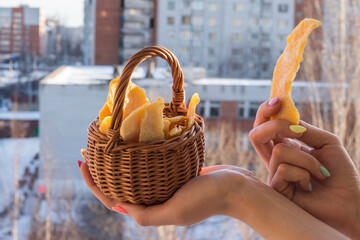 dried mango in a basket in the hands of a girl against the background of a winter city, the concept...