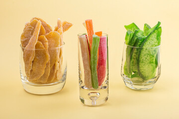 oriental sweets candied pineapple with mango and pomelo in glasses on a yellow background