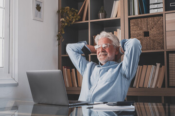 Happy satisfied caucasian mature man rest at home office sit with laptop hold hands behind head, dreamy old senior relax finished work feel peace of mind look away dream think of future success.