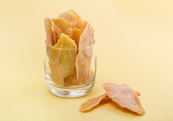oriental sweets candied mango in a glass on a yellow background with a copy of the space